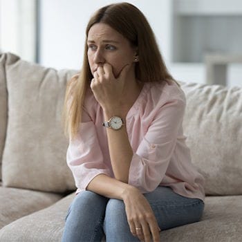 Sarah sitting on a couch looking overwhelmed with stress