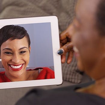 Gloria laughing while on a video call with her daughter