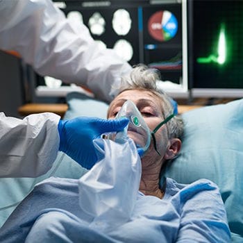 A COVID patient with a breathing mask and heart monitor