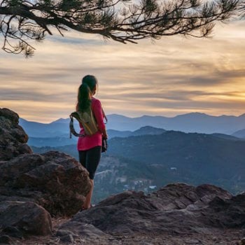Savannah watching the sunrise over rolling mountains across the distance