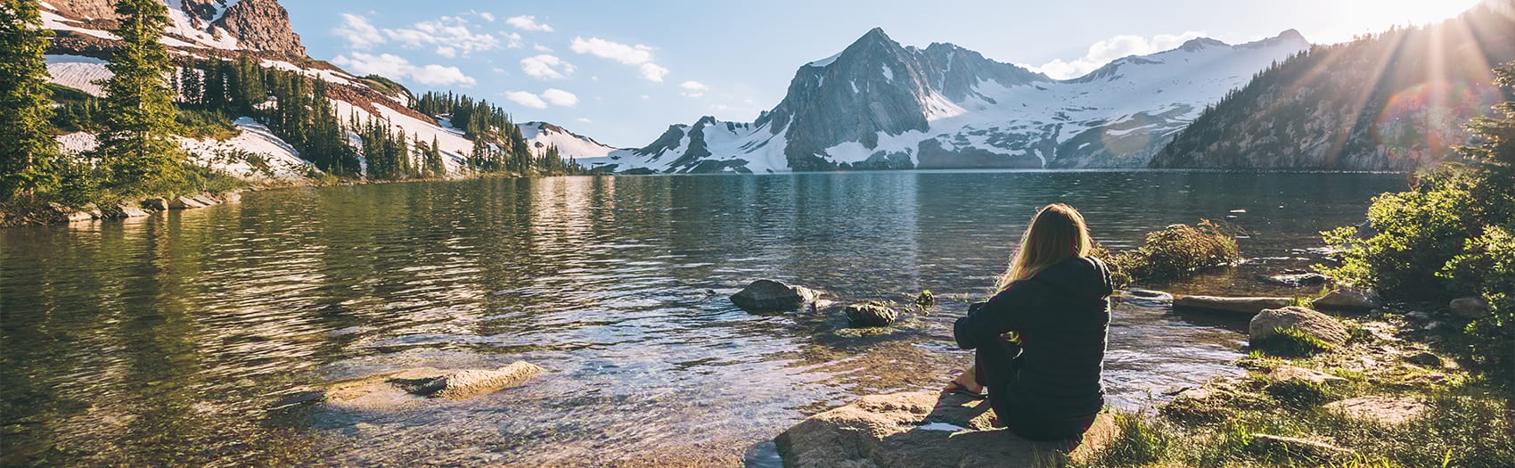 A woman sitting at the edge of an alpine river