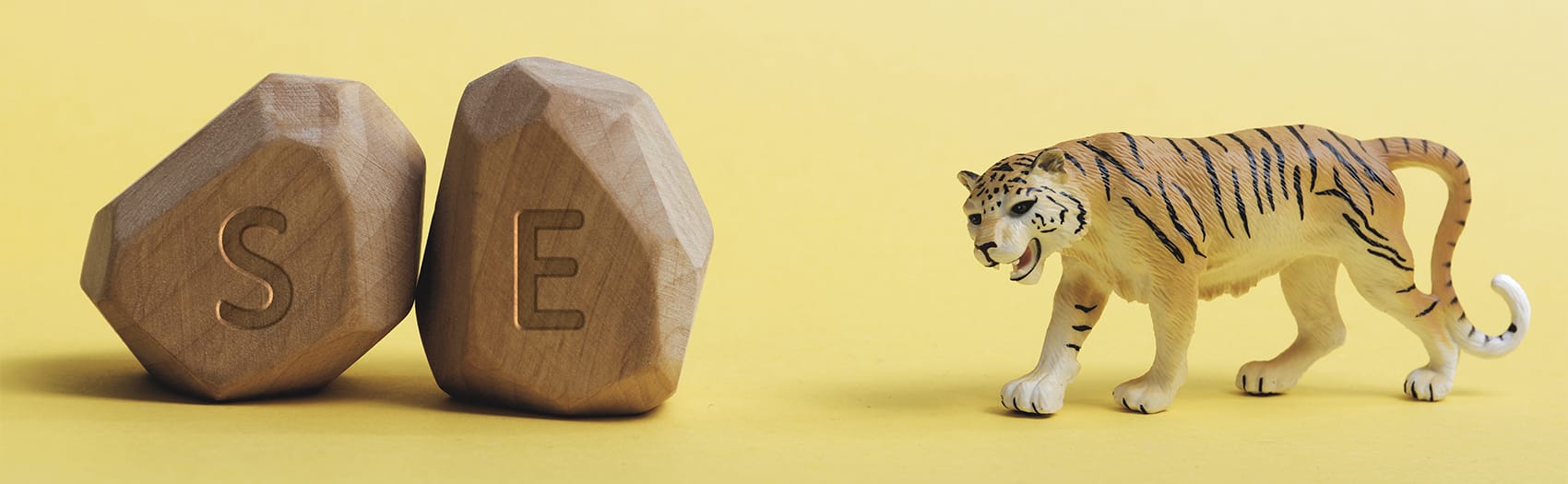 A toy tiger next to wooden blocks with the letters S and E