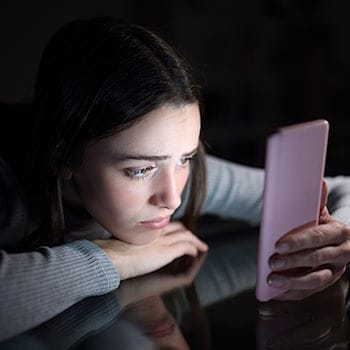 A bored-looking girl staring at her phone