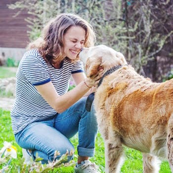 A woman playfully nuzzling her old dog's nose