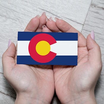 A business card-sized Colorado state flag in a woman's hands